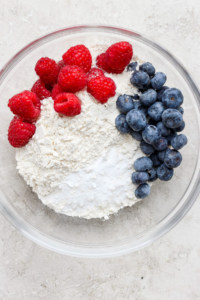 A bowl with flour, berries and blueberries.