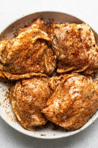 Seasoned chicken breasts in a white plate.