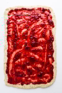 A square of dough with raspberry jam on it.