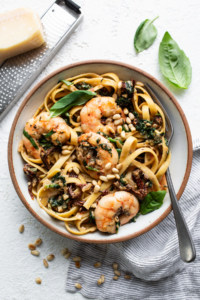 A bowl of pasta with shrimp and basil.