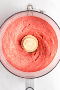Top view of a food processor containing freshly blended strawberry puree.