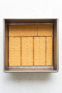 Rectangular graham crackers neatly arranged in a metal baking tray on a white textured background.