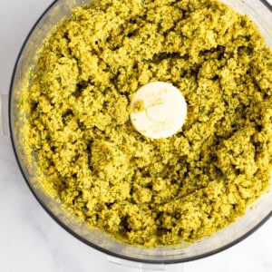 A food processor filled with blended green pesto.