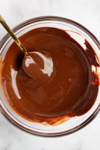 A bowl of melted chocolate with a spoon in it.