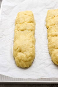 Two unbaked pastry dough logs on parchment paper, placed on a baking sheet.