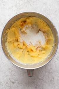 Mixing bowl with creamed butter and sugar on a textured surface.